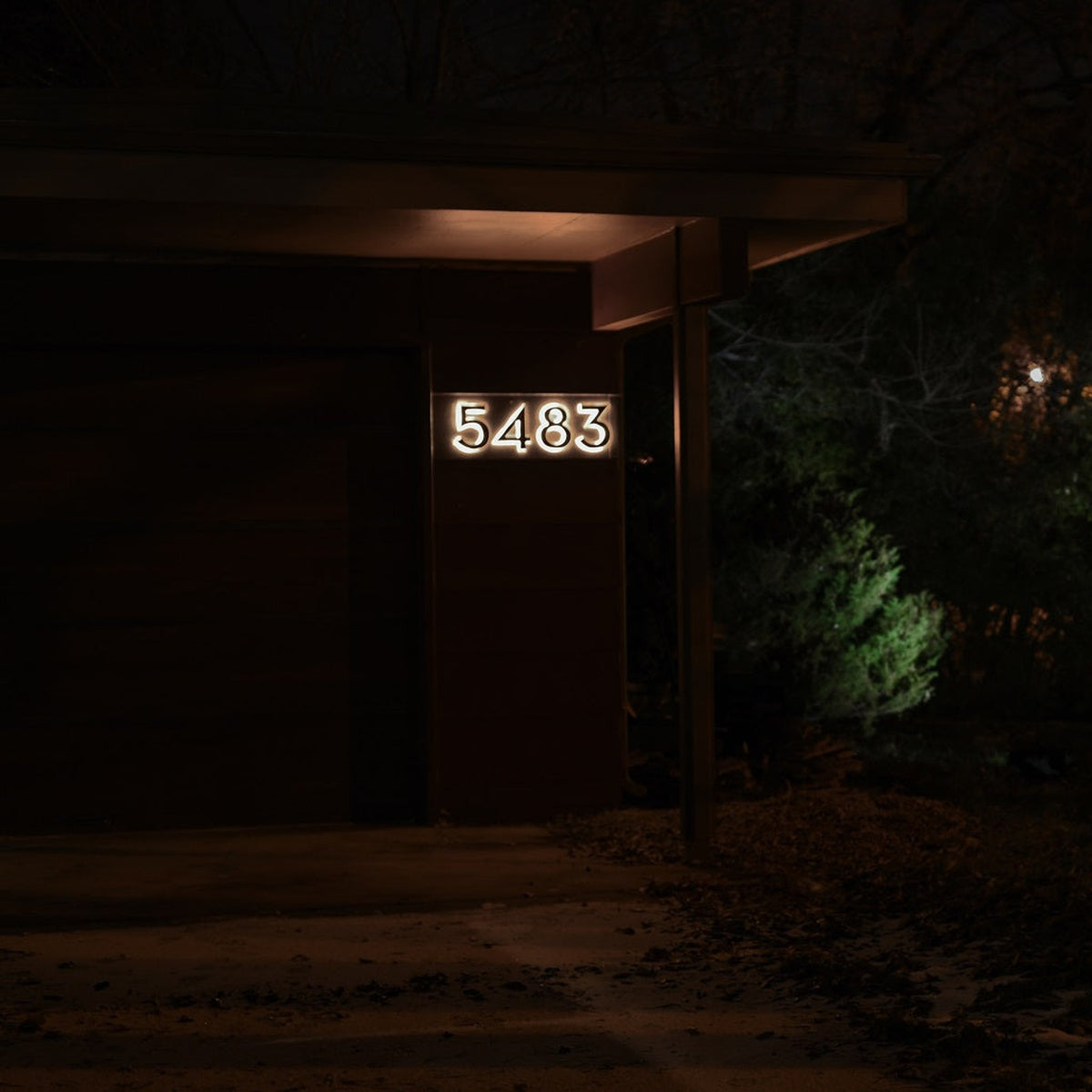 Black backlit house numbers 5483 seen from the street at night